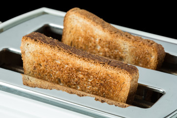 Closeup of toasted bread and toaster on black background