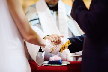 Bride and groom's hands wrapped in priest's cassock