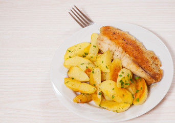 Fried fish fillet and potatoes in a plate