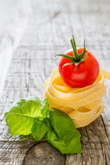 Dry pasta and cherry tomatoes, rustic wood background