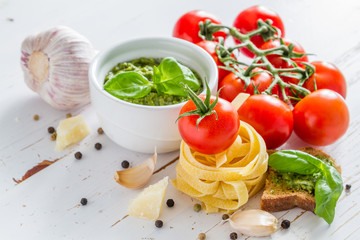 Pesto sauce pasta and tomatoes, white wood background