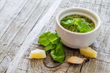 Pesto sauce in bowl, rustic wood background
