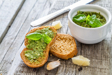 Pesto sauce in bowl, rustic wood background