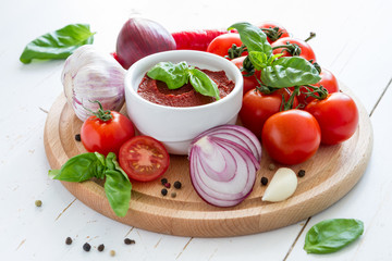 Tomato sauce and ingredients on white wood background