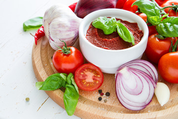 Tomato sauce and ingredients on white wood background