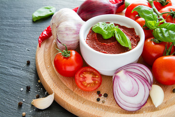 Tomato sauce and ingredients on dark stone background