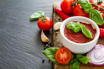 Tomato sauce and ingredients on dark stone background
