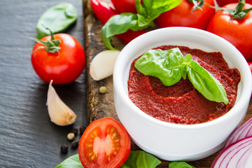 Tomato sauce and ingredients on dark stone background