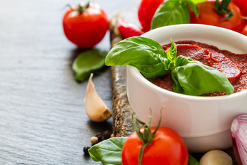 Tomato sauce and ingredients on dark stone background