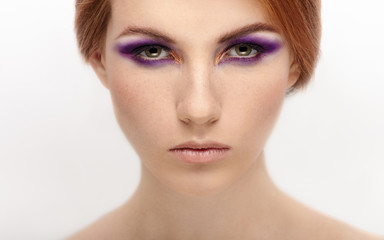 Fototapeta premium Closeup beauty portrait of a young beautiful calm redhead woman with violet eyes makeup