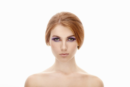 Closeup beauty portrait of a young beautiful redhead woman with violet eyes makeup and naked shoulders on isolated background
