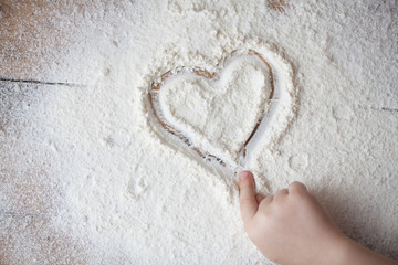 Heart of flour on wooden desk painted by a child