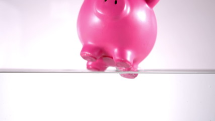 Pink piggy bank falling in water - Powered by Adobe
