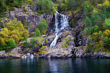 Fototapeta na wymiar small and idyllic waterfall in the tree covered mountains surrounding Lysefjord in Norway