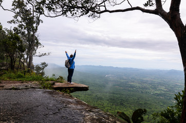 people raising hands at cliff
