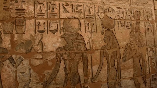 Ancient Egyptian hieroglyphic carvings on a temple wall at Medinat Habu in Luxor