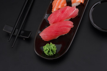 Premium quality sushi rolls with ginger wasabi and soy sauce over black background