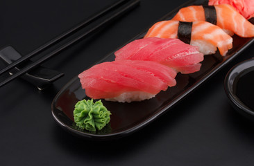Premium quality sushi rolls with ginger wasabi and soy sauce over black background