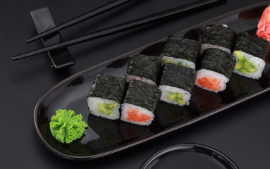 Premium quality sushi rolls with ginger wasabi and soy sauce over black background