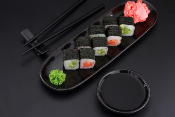 Premium quality sushi rolls with ginger wasabi and soy sauce over black background