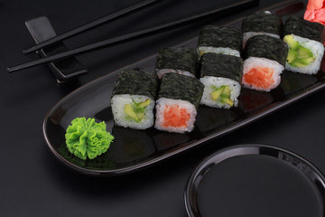 Premium quality sushi rolls with ginger wasabi and soy sauce over black background