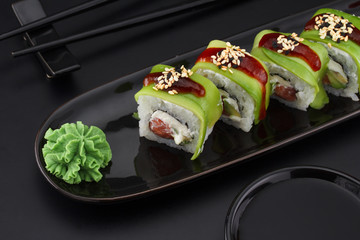 Premium quality sushi rolls with ginger wasabi and soy sauce over black background