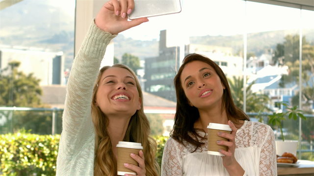 Pretty girls taking a selfie with coffee cups