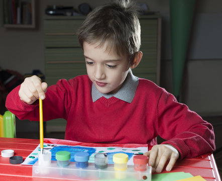 young boy is painting a paint. chaild painter in a room.