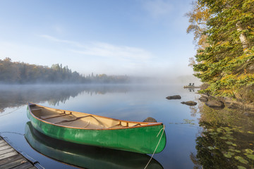 Naklejka premium Green Canoe Tied to Dock