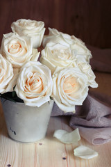 bouquet of white roses in a bucket on a wooden background