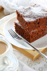 two pieces of plum cake with chocolate and almonds on a white pl