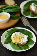 Poached egg on a piece of bread with spinach on the wooden table
