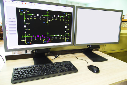 Computers and monitors with schematic diagram for supervisory, control and data acquisition in modern electrical control room