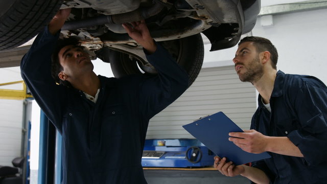 Handsome mechanics overhauling a car