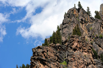 Cliff face of a mountain in the Gallatin Mountain Range rises rugged and steep into a vivid blue sky.