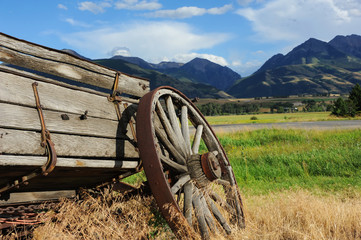 Broken down wagon is being overtaken by weeds.  Wagon sits with a beautiful view of the Absaroka Mountains in Paradise Valley, Montana.