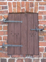 A weathered, closed wooden window in an old brick building,  Bild