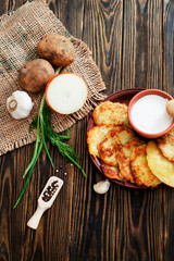 Obraz na płótnie Canvas national russian and ukrainian cuisine, potato pancakes with sour cream , herbs , garlic and spices on a wooden background