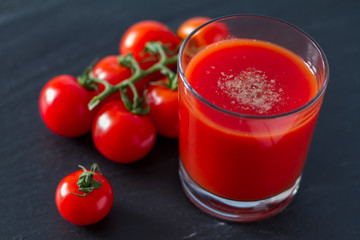 Tomato juice in glass, dark stone background