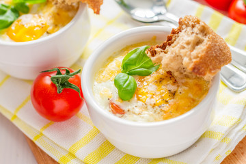 Egg cocotte  in white ramekin with tomato and basil
