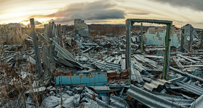 Apocalyptic landscape.The remains of destroyed houses covered with snow at sunset