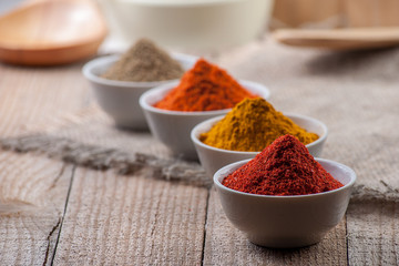 Spices in bowls on wooden background