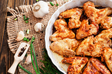 
baked chicken wings and garlic marinade with herbs on a wooden background