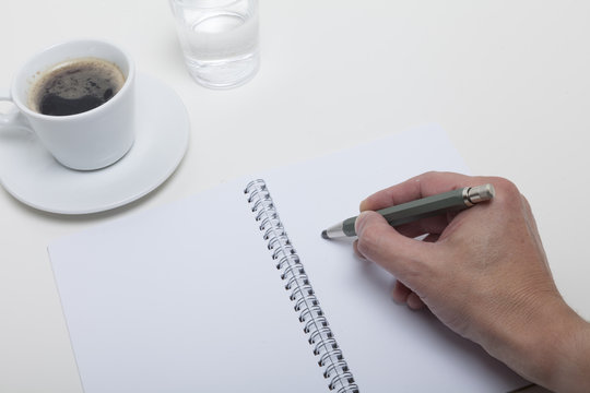 Grafiker skizziert etwas von Hand in sein Notizheft, das mit ein