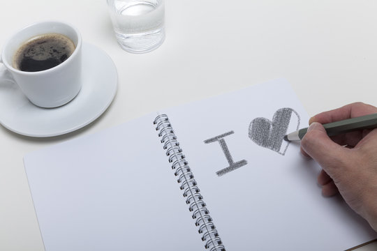 I Love You skizziert von Hand in ein Notizbuch. Am Rande eine Ta