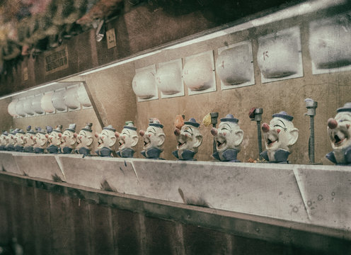 Clown Water Gun Game Vintage. A classic water gun clown balloon carnival game. Old, aged looking clown heads and numbered flashing lights. Edited with a vintage film effect.