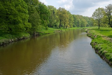 Fototapeta na wymiar River Nisa in the park near castle of Prince Pueckler in Bad Muskau in Saxony, Germany. Muskauer Park is part of UNESCO World Heritage Site.