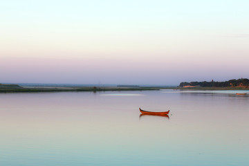 Une barque isolée au milieu du fleuve Irrawaddy, calme au coucher de soleil