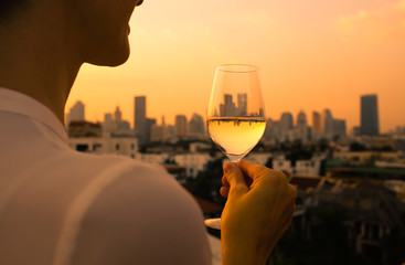 Woman celebrating with a glass of wine and city view.