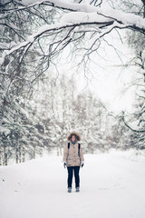 Naklejka premium A girl wearing warm winter clothes in winter, gloomy forest. Retro filtered look.